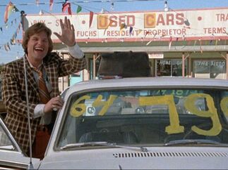 Kurt Russell en la película Used Cars saludando a un cliente en la explanada de un automóvil